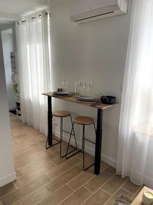a table with two stools in a room with white walls at Bleu Suprême balnéo in Vierzon