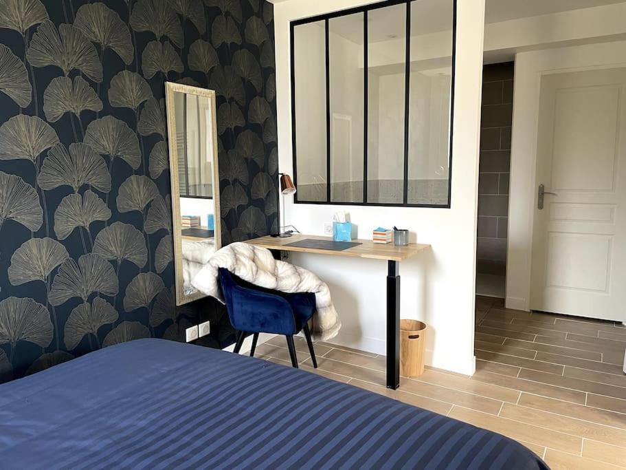 a bedroom with a bed and a desk with a mirror at Bleu Suprême balnéo in Vierzon