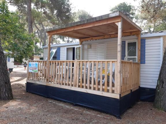 Casa pequeña con porche y terraza de madera. en Happy Camp mobile homes in Camping La Vecchia Torre, en Gallipoli