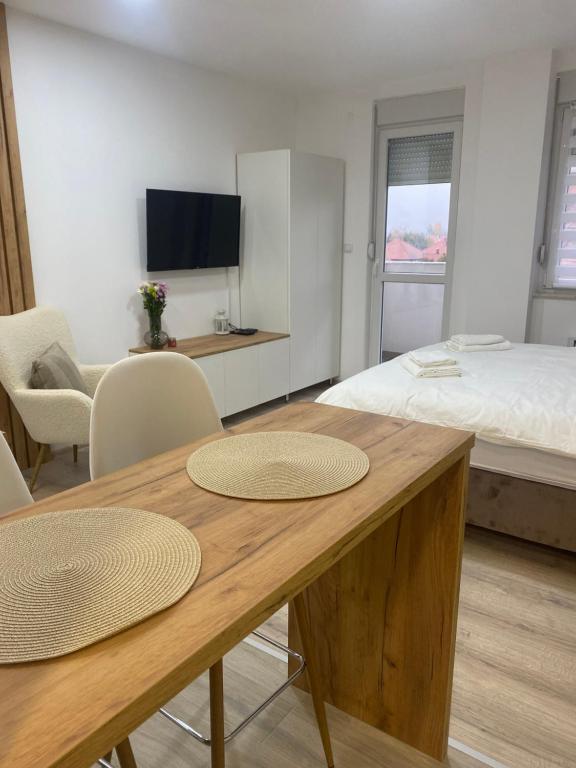 um quarto com uma cama e uma mesa com duas cadeiras em Apartman Enigma em Ruma