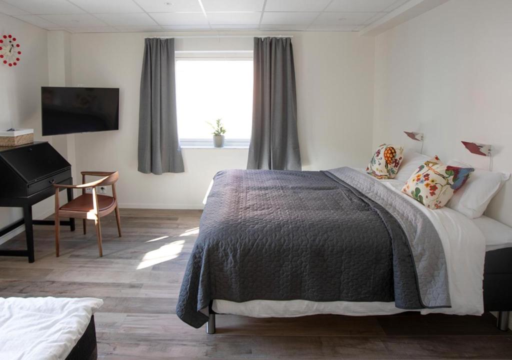 een slaapkamer met een bed, een bureau en een piano bij Hotell Havsporten in Karlholmsbruk