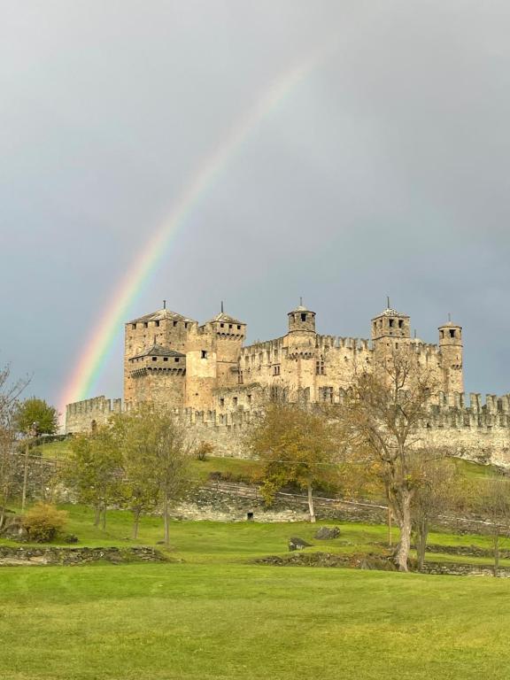 a rainbow in front of a castle with a field at À la Bouteucca in Fenis