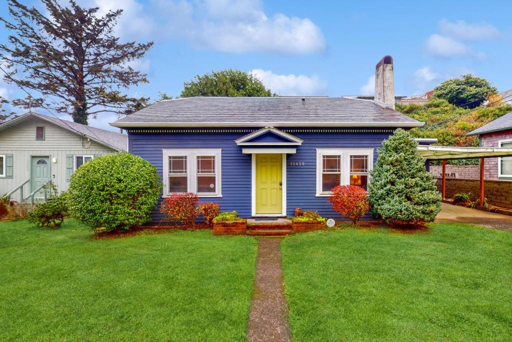 a blue house with a yellow door in a yard at Cliff Retreat in Rockaway Beach