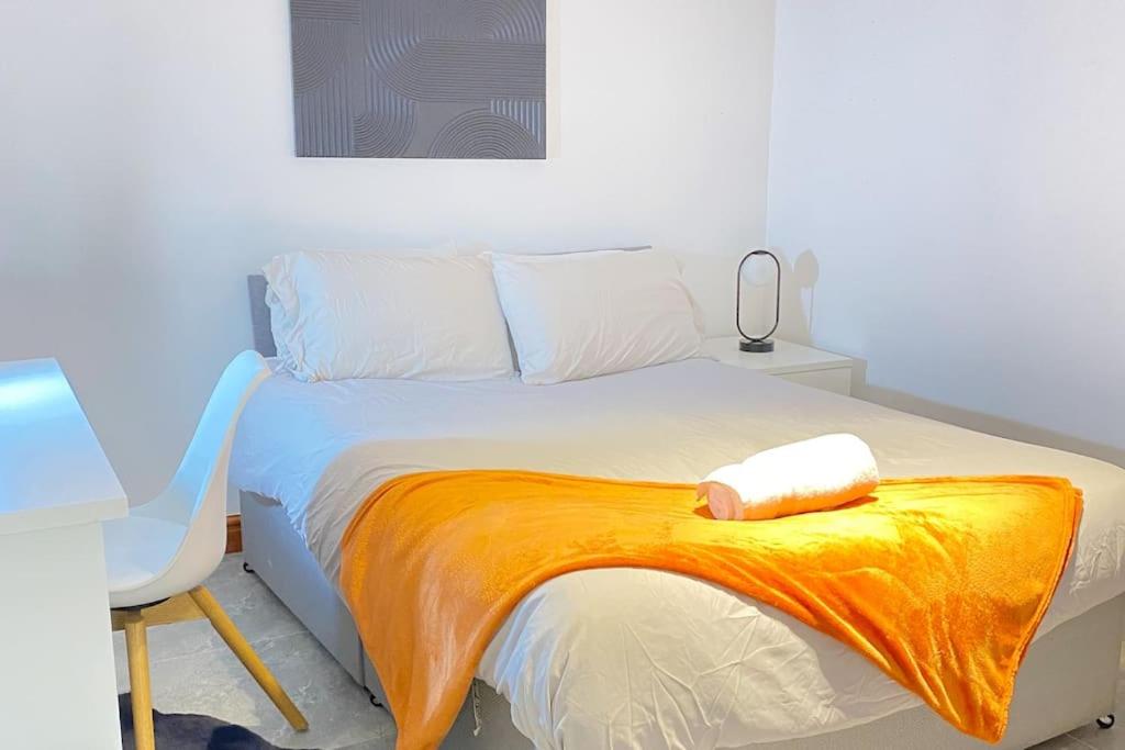 a bedroom with a bed with an orange blanket on it at Horizon Haven in Manchester