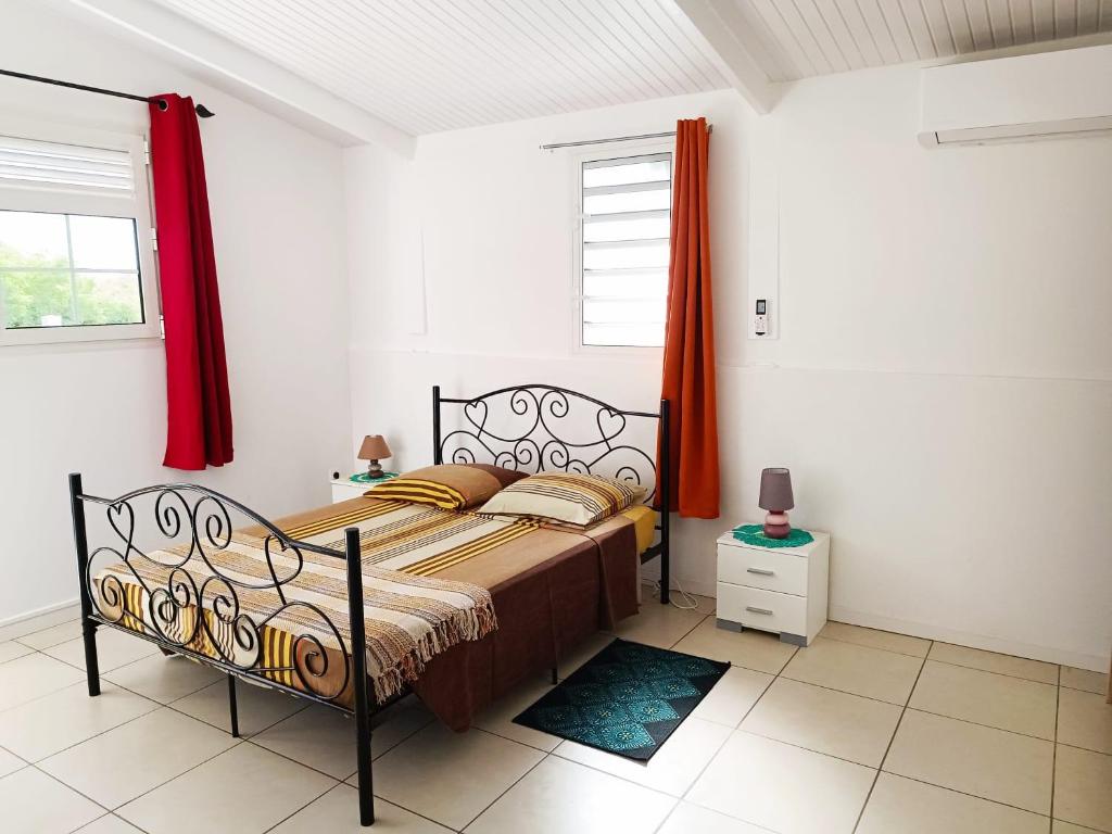 a bedroom with a bed and a red curtain at La belle Martinique in Sainte-Luce