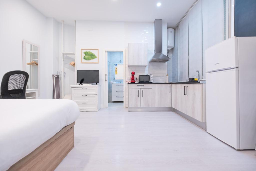 una cocina con armarios blancos y una cama en una habitación en ABC Apartments Madrid, en Madrid