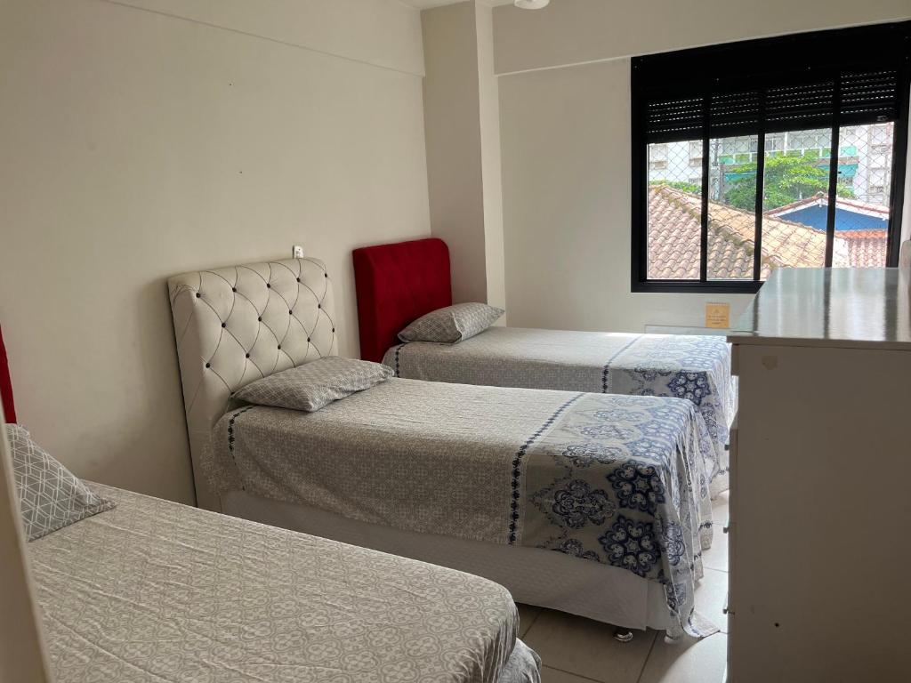 um quarto com duas camas e uma janela em Apartamento amplo a menos de 400 metros da praia localizado próximo a praça da Brunella, área nobre do Guarujá. no Guarujá