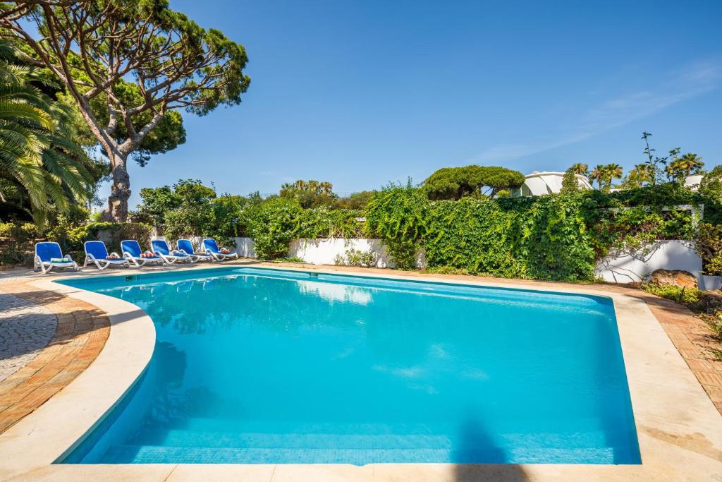 una piscina con sedie blu e alberi di Villa Quadradinhos 38Q - great 4BR Vale do Lobo villa with AC Private Pool a Vale do Lobo