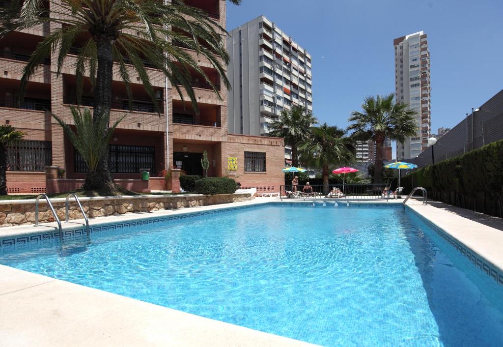 a large swimming pool with a large blue umbrella at Apartamentos La Caseta - SABESA in Benidorm