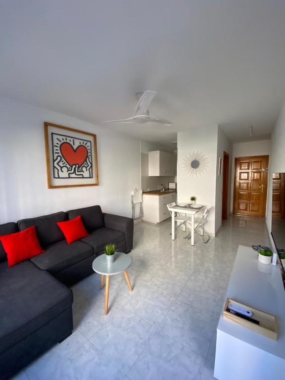 sala de estar con sofá negro y almohadas rojas en Apartamento moderno y familiar Live Santa Cruz Centro, en Santa Cruz de Tenerife