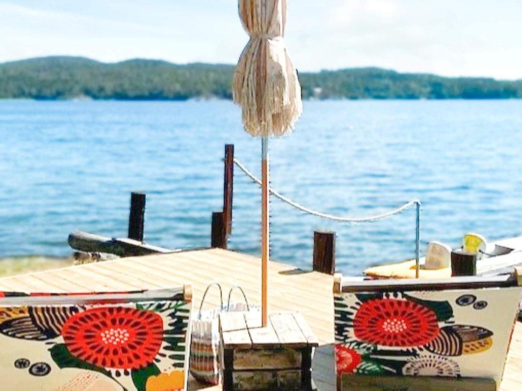 a dock with an umbrella and a table with a chair at Holiday home SANDÖVERKEN in Sandöverken