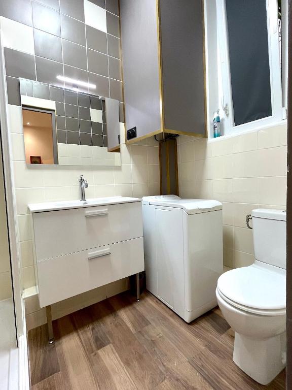 a white bathroom with a toilet and a sink at Loft Vincennes in Vincennes