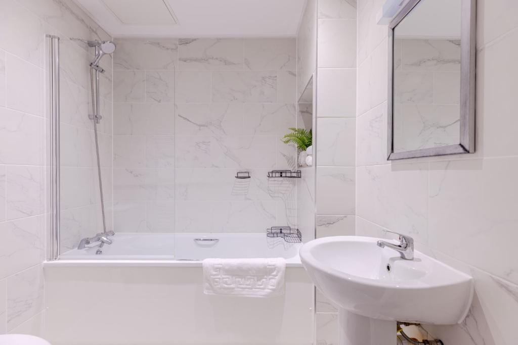 a white bathroom with a sink and a bath tub at Boutique Vertigo Apartment Central Kingston/London in Kingston upon Thames