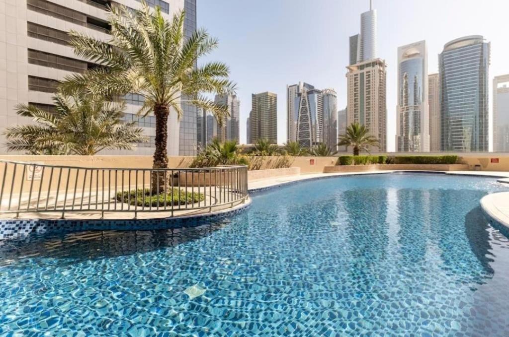 a swimming pool with a palm tree in a city at Luxury 1 Bedroom On Marina Walk in Dubai