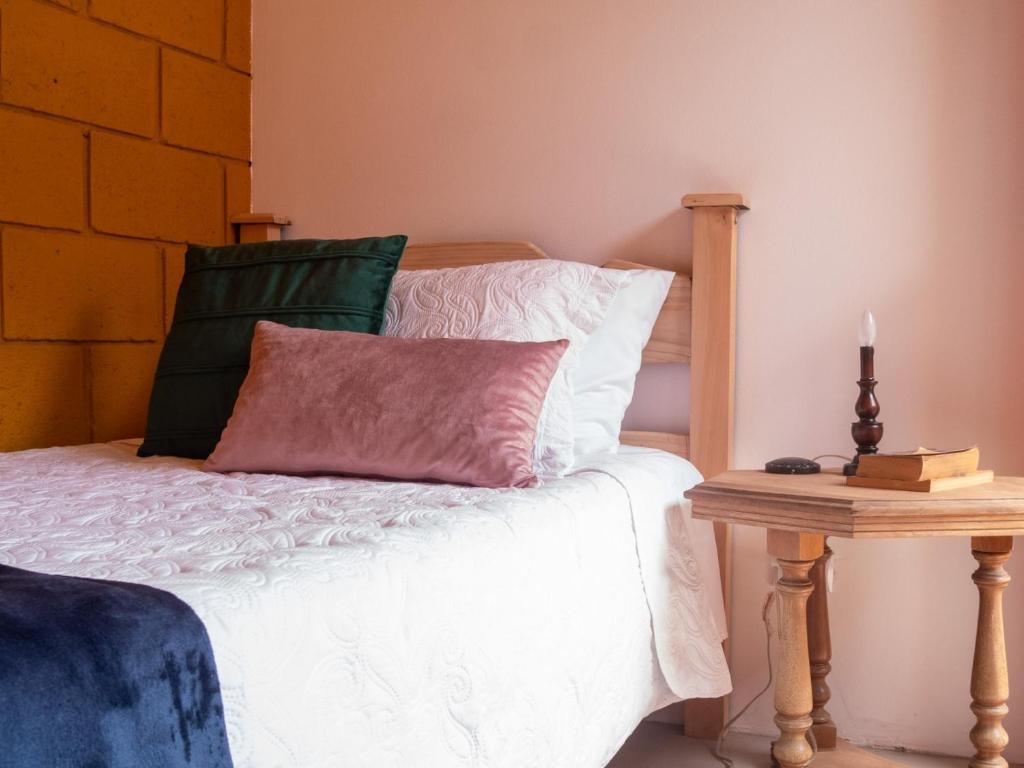 1 cama con almohada rosa y mesa auxiliar en Lolas Hostal (Hab. privada) baño compartido, en San José