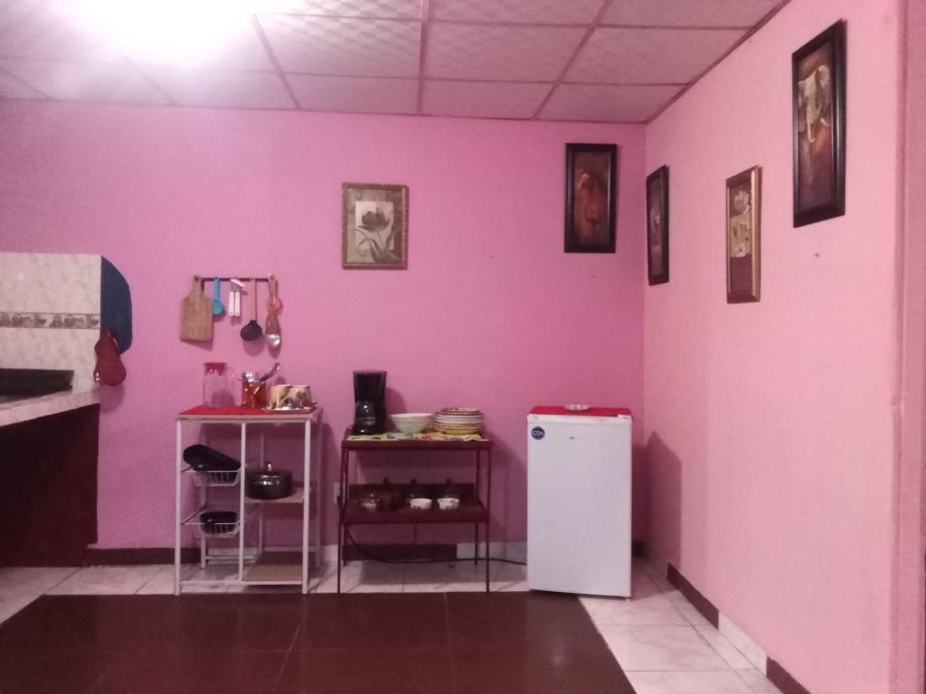 Zimmer mit einer rosa Wand und einem Kühlschrank in der Unterkunft Beautiful villa for singles, couples, families and groups cozy stay in La Chorrera