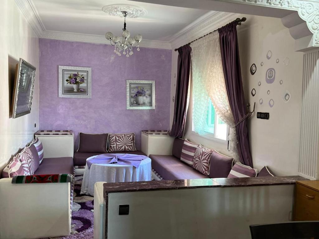 a living room with purple walls and purple furniture at Appartandalus in Larache
