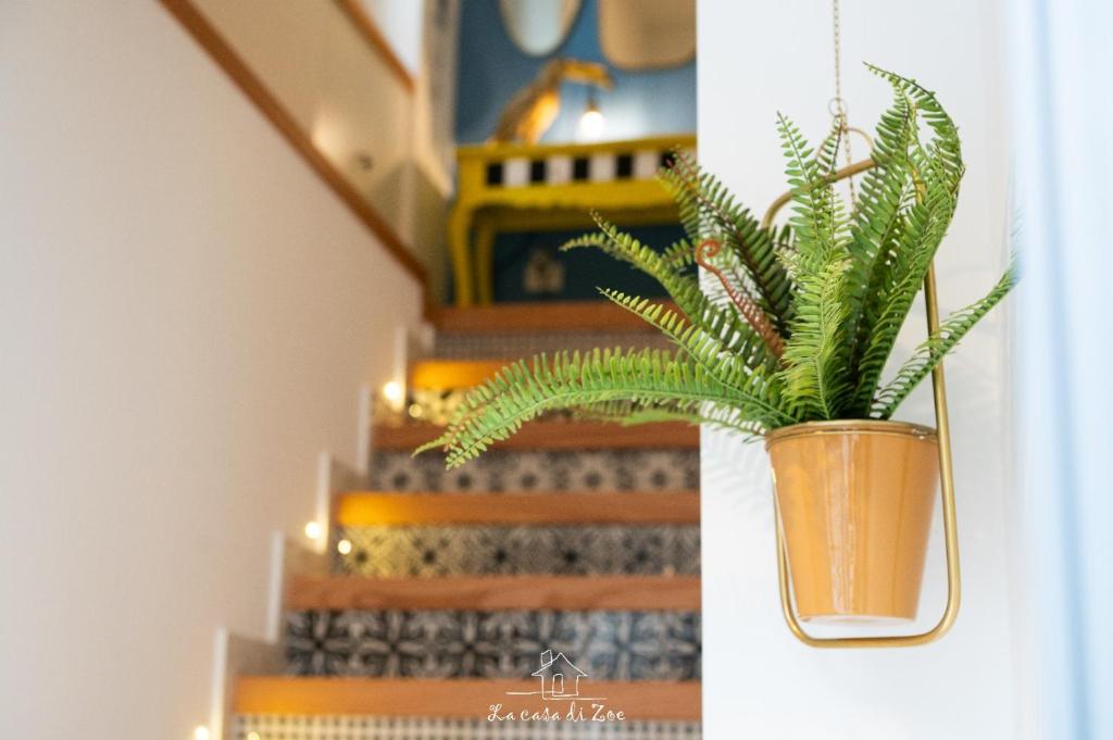 una planta en un jarrón en una pared al lado de las escaleras en LA CASA DI ZOE, en Manfredonia