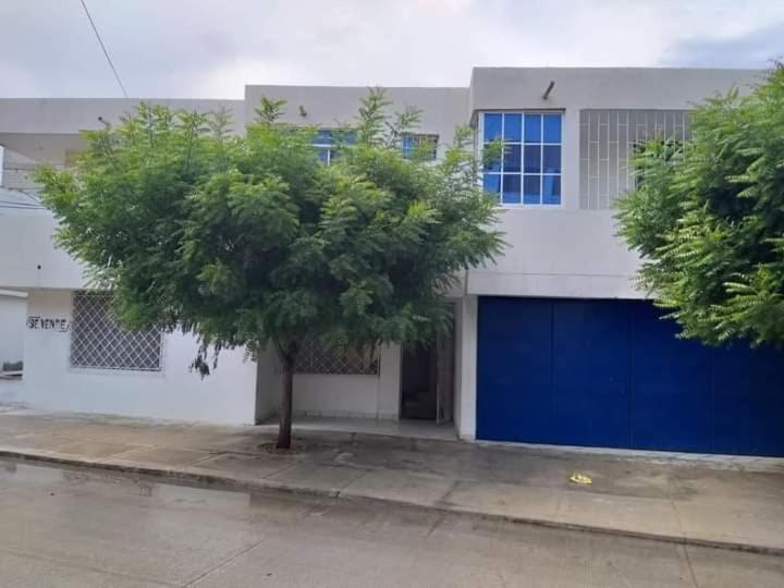 un árbol frente a un edificio con un garaje azul en Cómodo apartamento en el rodadero en Rodadero