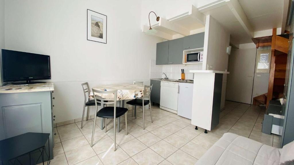a small kitchen with a table and chairs in a room at A proximité du cinéma et du marché, à 150 m de la plage in La Couarde-sur-Mer