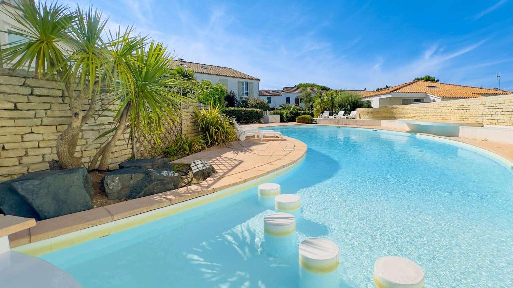 a swimming pool in a yard with a palm tree at A proximité du cinéma et du marché, à 150 m de la plage in La Couarde-sur-Mer