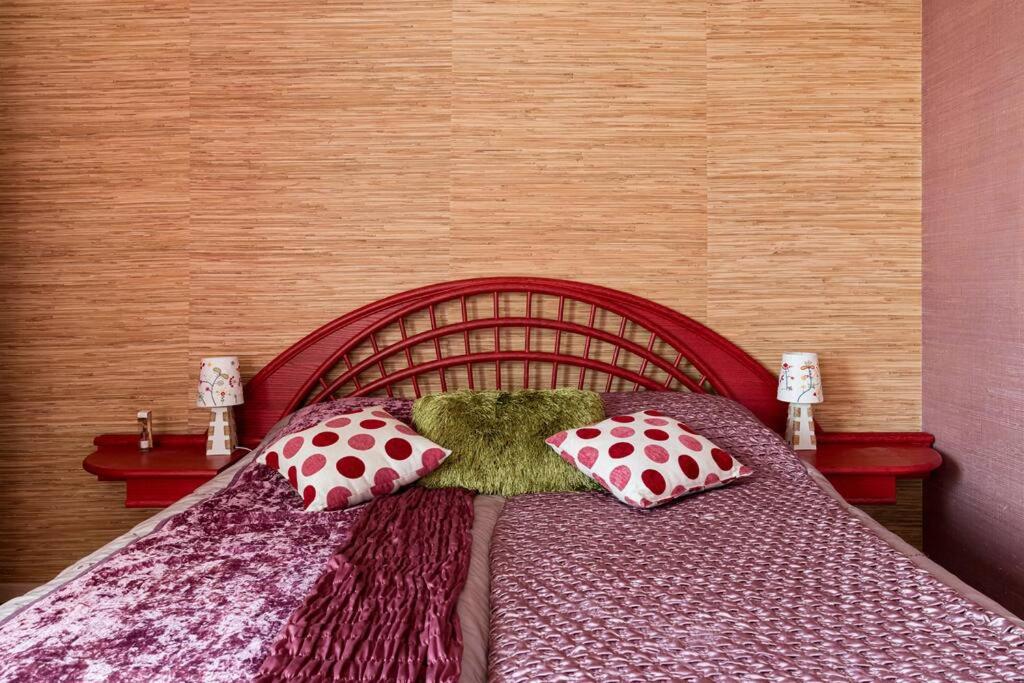 a bedroom with a red bed with pillows on it at Celestine Parisien terrasse parking in Saint-Étienne