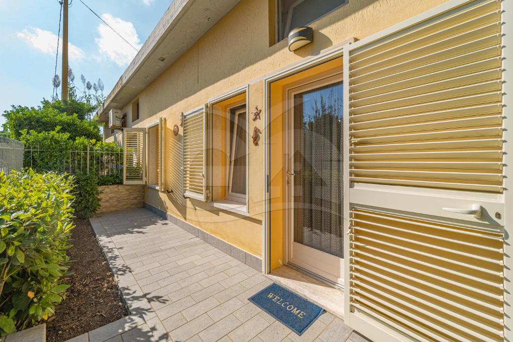 a house with a yellow door and a sidewalk at Villino Aloe - Goelba in Marina di Campo