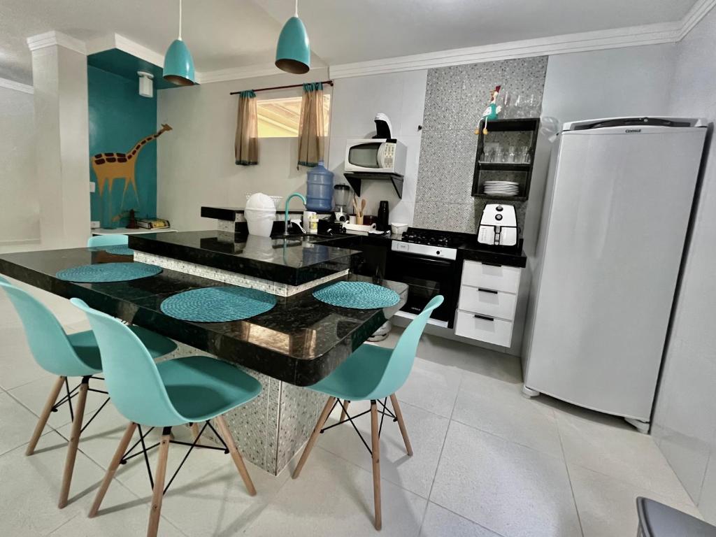 cocina con mesa negra y sillas azules en Bella Peroba Flats #4 Tiffany - Maragogi - AL ' Acessibilidade Kids en Maragogi