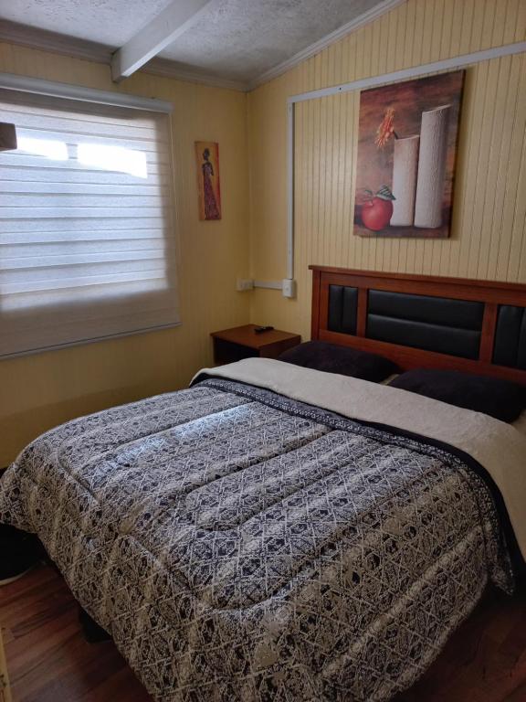 Un dormitorio con una cama y una ventana con una persiana en Cabañas y hostal sol de oriente, en Puerto Montt