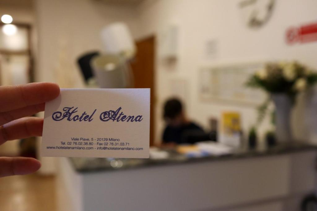 una persona con una tarjeta delante de un mostrador en Hotel Atena, en Milán
