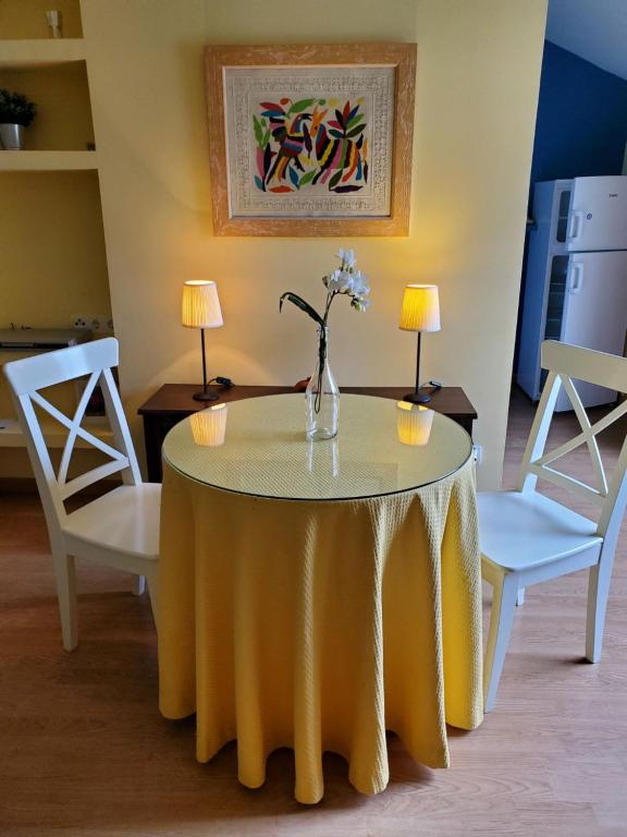 a yellow table with a vase of flowers on it at El Ático in Tordesillas