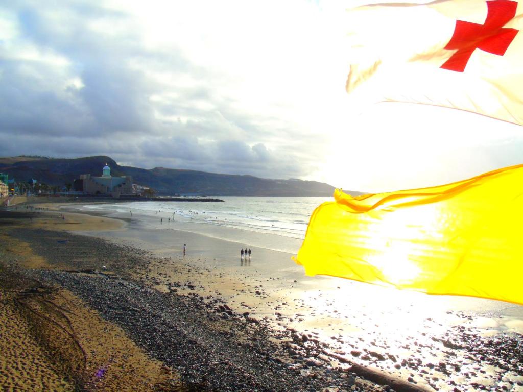 Eine Flagge am Strand mit Menschen im Wasser in der Unterkunft Happy Waves Home in Las Palmas de Gran Canaria