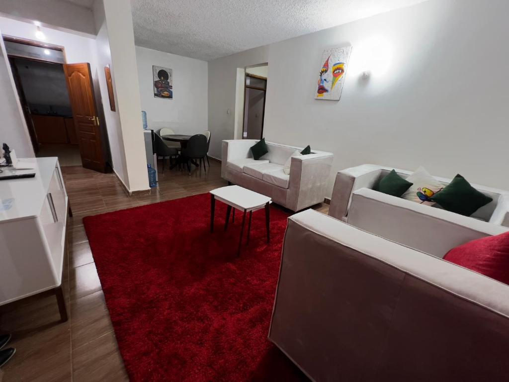 una sala de estar con 2 sofás blancos y una alfombra roja en Classic all ensuit 3 bedroom in kisumu town, en Kisumu