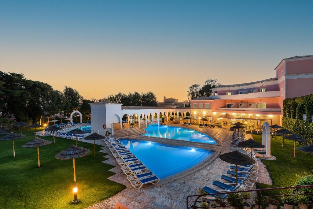 uma imagem de um hotel com piscina e guarda-sóis em Clube Vilarosa em Portimão