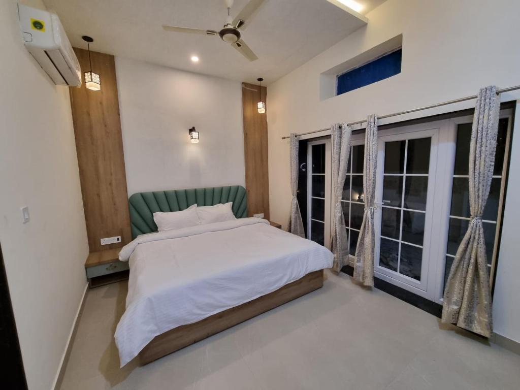 ウダイプールにあるGreen Villa - Peaceful Location, Luxury Rooms - 200 Meters from Bus Stand & 500 Meters from Udaipur City Railway Stationのベッドと大きな窓のある寝室