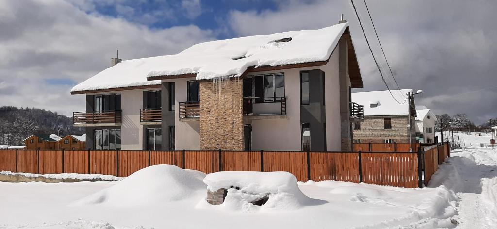 dom pokryty śniegiem z płotem w obiekcie Townhouse in Mountains. w mieście Bakuriani