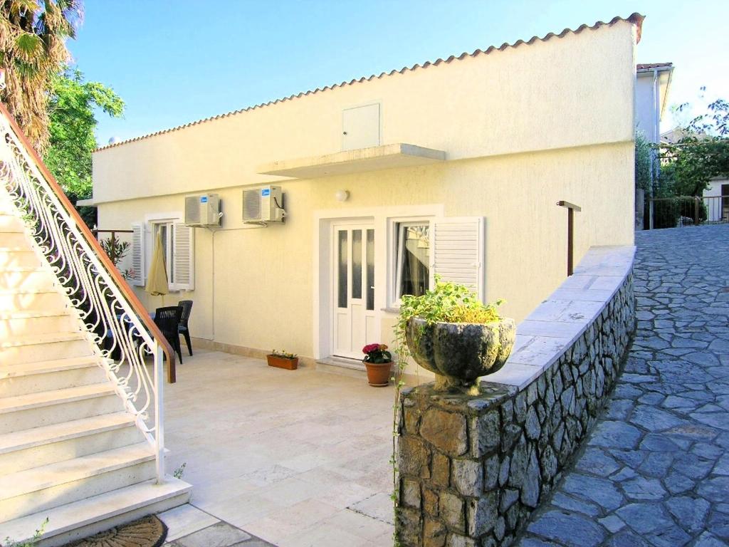 a house with a stone wall next to a staircase at Apartment Maja in Krk