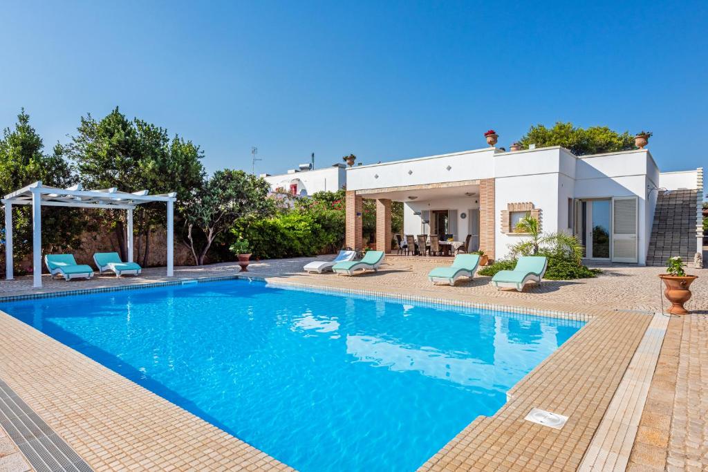 uma piscina com cadeiras azuis e uma casa em Villa Vanessa em Castrignano del Capo