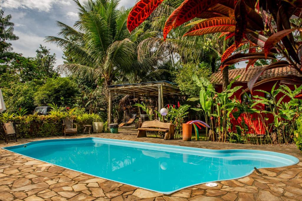 een zwembad tegenover een resort met palmbomen bij Casa da Praia in Paraty