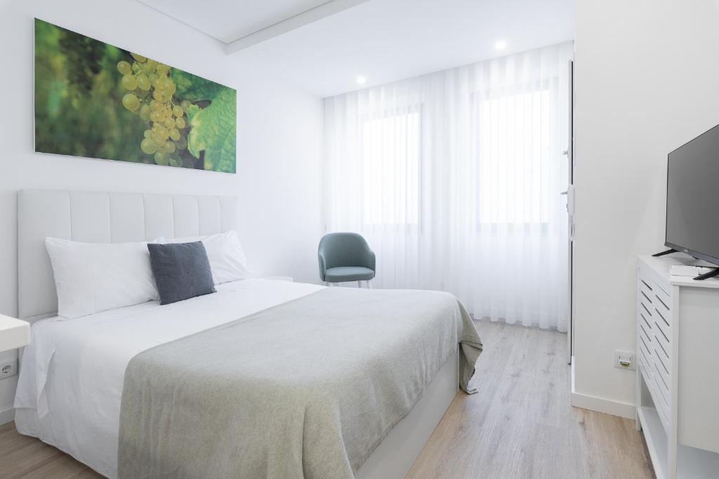 a white bedroom with a bed and a chair at FAFEL LITTLE HOUSE - Quinta de Cravaz in Lamego
