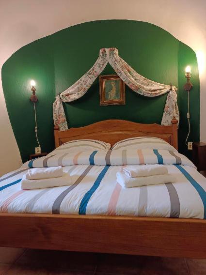 a bed with a green headboard with two pillows on it at Guest House Olšakovský in Český Krumlov
