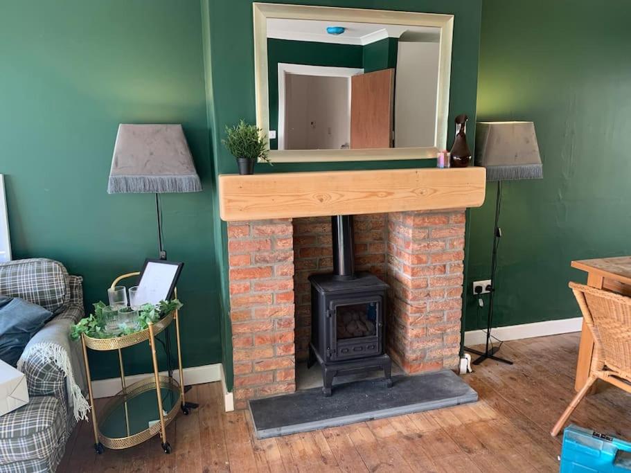 sala de estar con chimenea de ladrillo y espejo en Tenby 2 bed flat with parking, plus pet, en Tenby