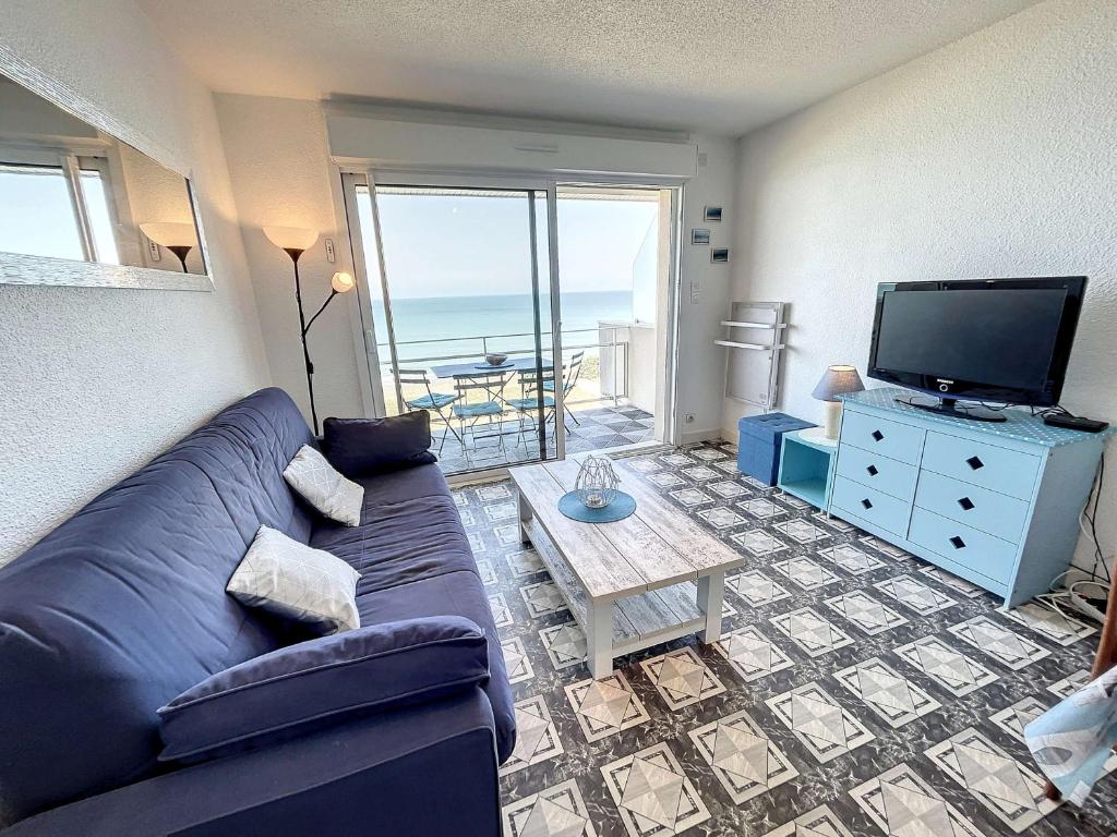 un salon avec un canapé bleu et une télévision dans l'établissement Appartement en front de mer avec balcon et parking privatif - FR-1-361-360, à Jullouville