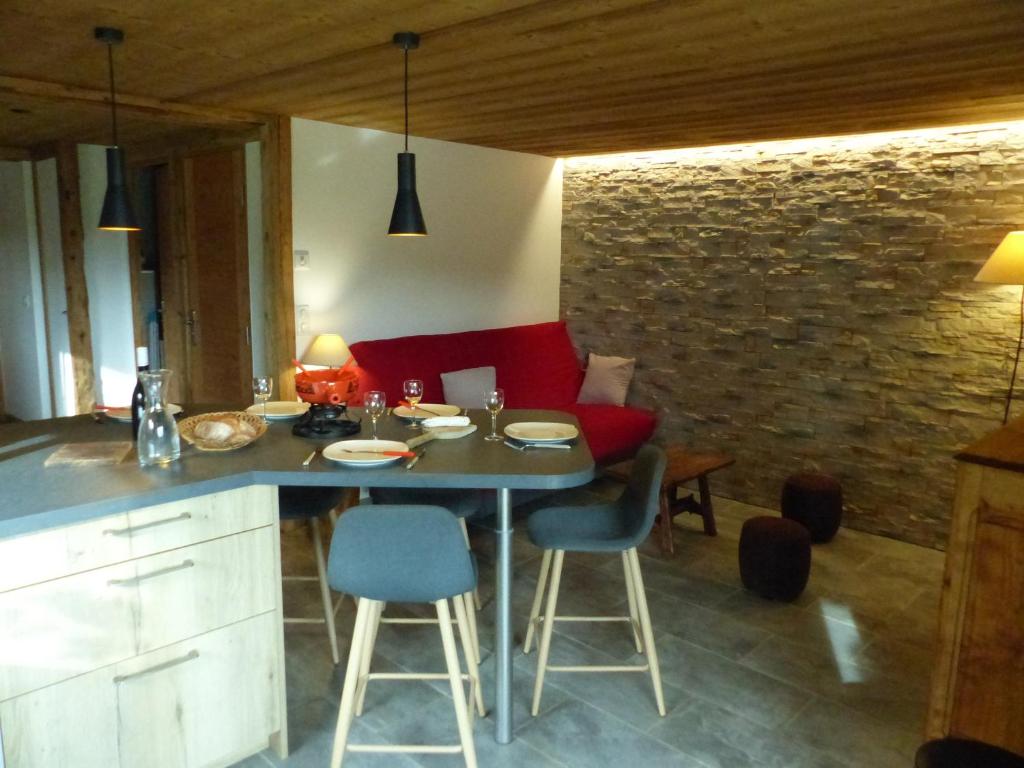 une cuisine avec une table et des chaises ainsi qu'un mur en briques dans l'établissement Charmant appartement en chalet historique avec bain norvégien, proche pistes et commodités - FR-1-467-96, au Grand-Bornand