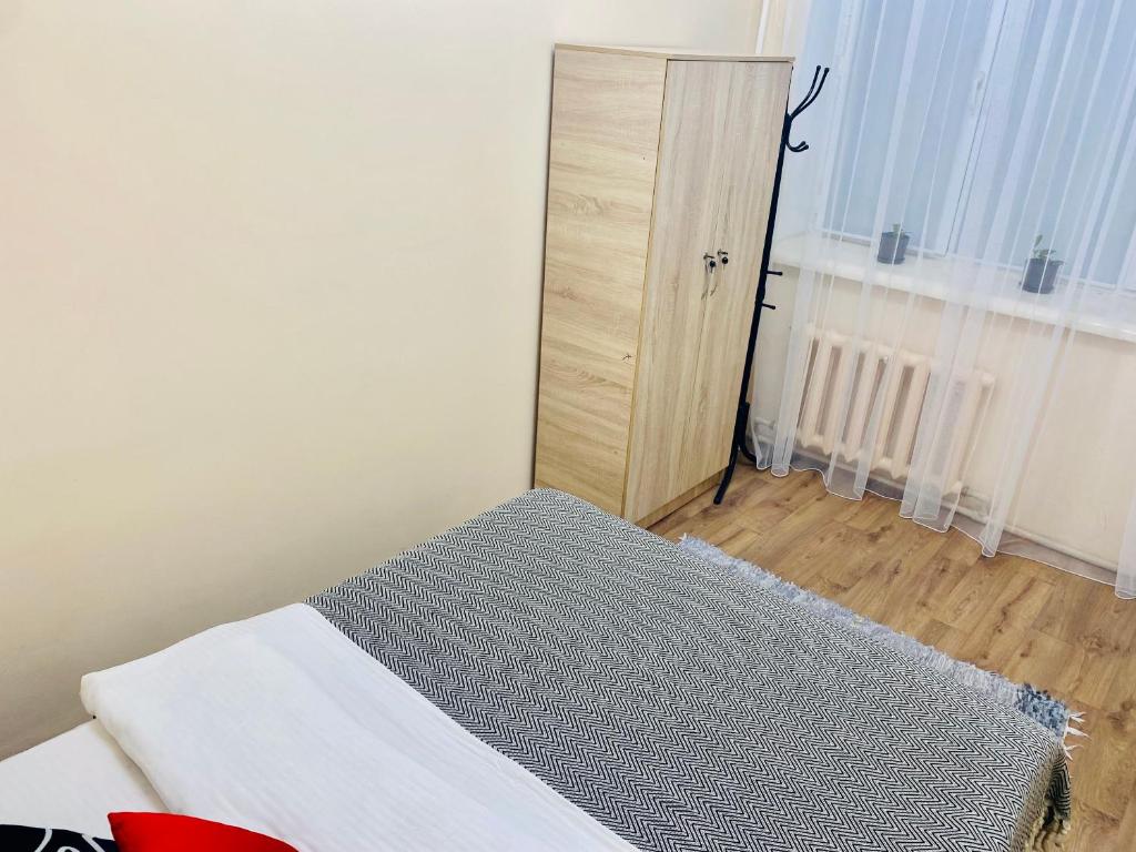 a bedroom with a bed and a wooden cabinet at Like Home Rooms in Almaty