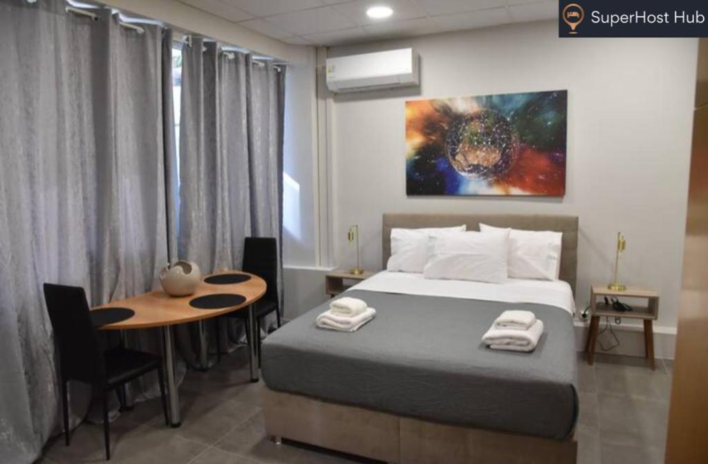 ein Schlafzimmer mit einem Bett, einem Tisch und einem Gemälde in der Unterkunft Athens Panormou Central Apartment Zeus by SuperHost Hub in Athen