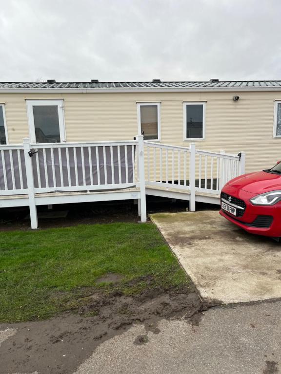 a house with a white fence and a red car at CW27 St Osyth Holiday Park with disability Ramp in Saint Osyth