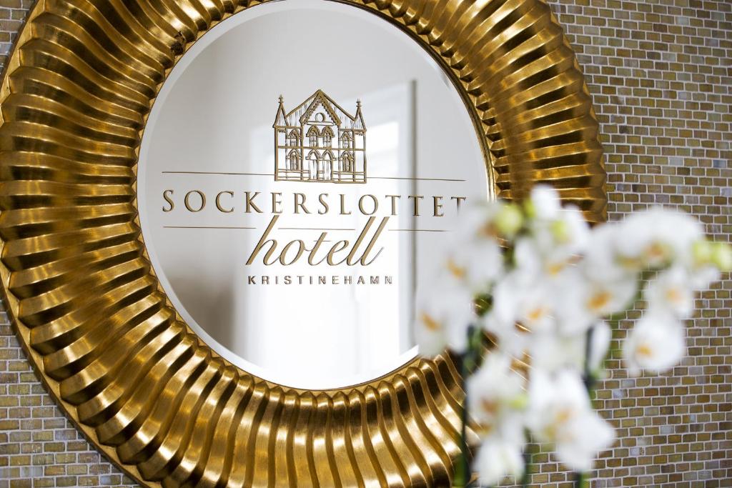 un miroir en or sur un mur de briques avec un panneau d'hôtel dans l'établissement Sockerslottet Hotell, à Kristinehamn