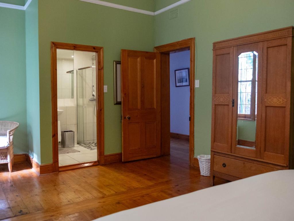 a room with green walls and wooden floors and doors at Charming Heritage Villa Tamboerskloof in Cape Town