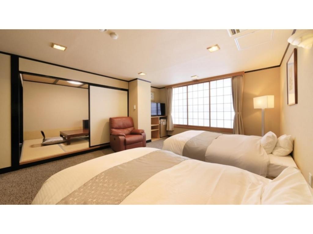 Pokój hotelowy z 2 łóżkami i krzesłem w obiekcie Ryokan Biyu no Yado - Vacation STAY 16236v w mieście Yokokura